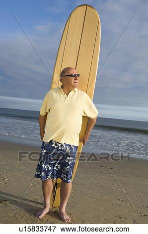 Senior man holding a surfboard View Large Photo Image Stock Photo - Senior man holding a surfboard. Fotosearch