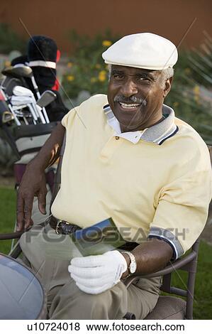 Stock Photo - Senior man holding golf score card, (portrait). Fotosearch