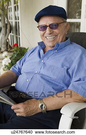Stock Image - Senior man relaxing on porch, (portrait). Fotosearch