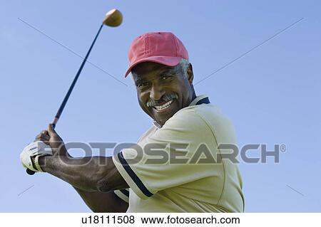 Senior man swinging golf club, (portrait), (low angle view) View Large Photo Image Stock Photo - Senior man swinging golf club, (portrait), (low angle view). Fotosearch