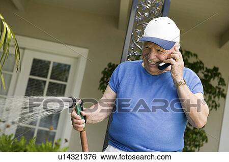 Senior man watering lawn, talking in mobile phone View Large Photo Image Stock Photograph - Senior man watering lawn, talking in mobile phone. Fotosearch