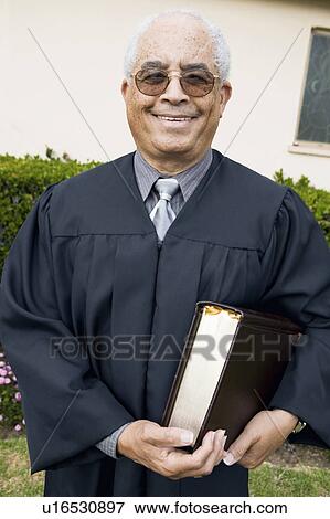 Stock Photo - Senior Preacher in garden with Bible, portrait. Fotosearch