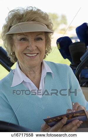Stock Photo - Senior woman holding golf score card, (portrait). Fotosearch