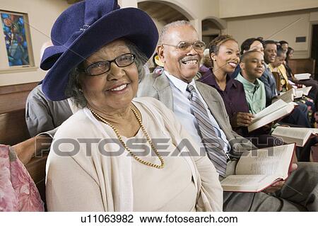 Stock Image - Senior Woman in Sunday Best among congregation at Church, portrait. Fotosearch