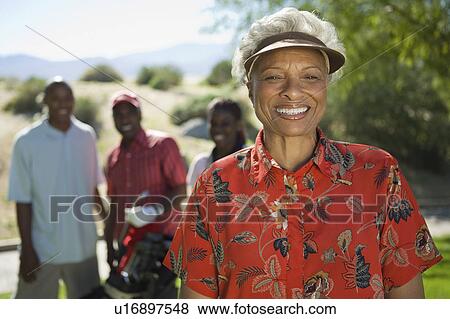 Stock Photo - Senior woman on golf course, (portrait), family in background. Fotosearch