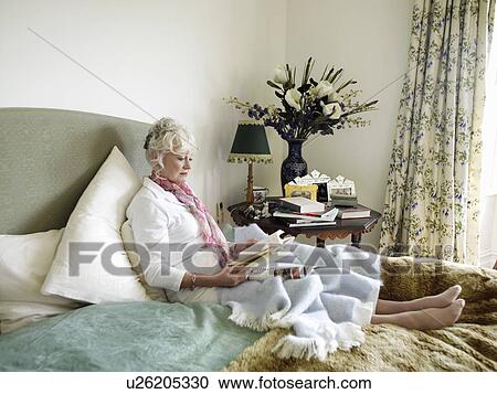 Senior woman sitting on bed, reading book View Large Photo Image Stock Image - Senior woman sitting on bed, reading book. Fotosearch
