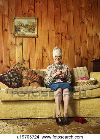 Picture - Senior woman sitting on sofa, knitting, (portrait). Fotosearch