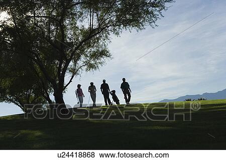 Stock Photo - Silhouettes of group of golfers walking on golf course. Fotosearch
