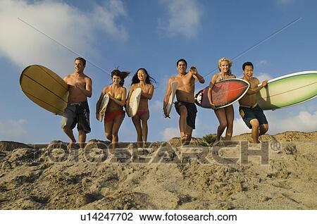 Six surfers carrying surfboards, running on beach View Large Photo Image Stock Image - Six surfers carrying surfboards, running on beach. Fotosearch