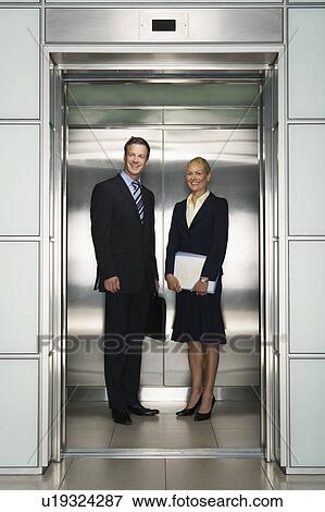 Smiling Businessman and Businesswoman in Office Elevator, portrait View Large Photo Image Stock Photo - Smiling Businessman and Businesswoman in Office Elevator, portrait. Fotosearch