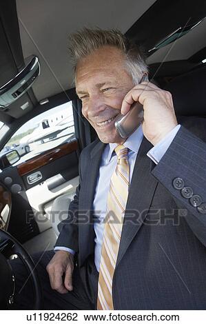 Smiling Businessman sitting in car, talking on mobile View Large Photo Image Stock Image - Smiling Businessman sitting in car, talking on mobile. Fotosearch