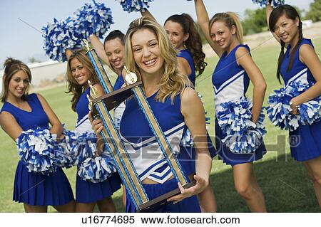 Stock Photography - Smiling Cheerleader holding trophy, (portrait). Fotosearch