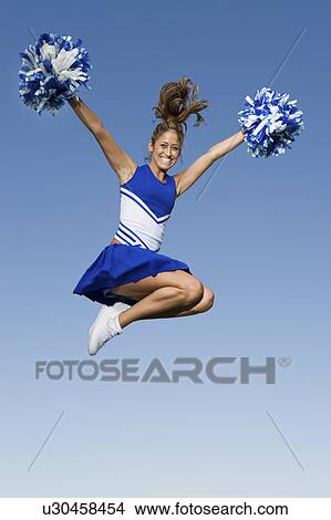 Smiling Cheerleader jumping in mid-air, (portrait), (low angle view) View Large Photo Image Picture - Smiling Cheerleader jumping in mid-air, (portrait), (low angle view). Fotosearch