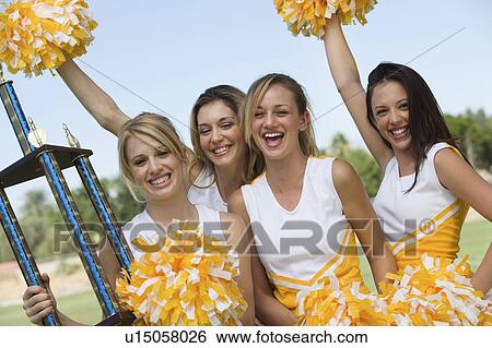 Smiling Cheerleaders holding trophy and pom-poms, (portrait) View Large Photo Image Stock Photograph - Smiling Cheerleaders holding trophy and pom-poms, (portrait). Fotosearch