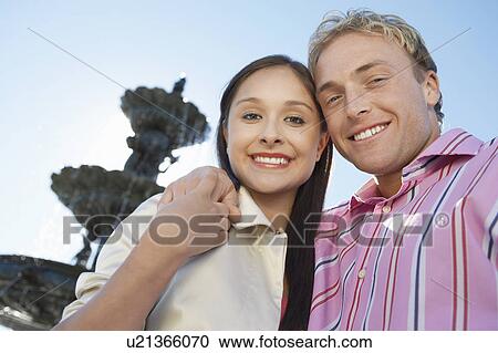 Smiling Couple, arms around, standing in Front of Fountain View Large Photo Image Stock Image - Smiling Couple, arms around, standing in Front of Fountain. Fotosearch