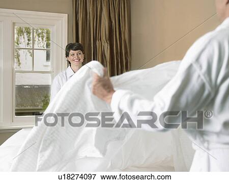 Smiling couple making bed together View Large Photo Image Stock Photo - Smiling couple making bed together. Fotosearch