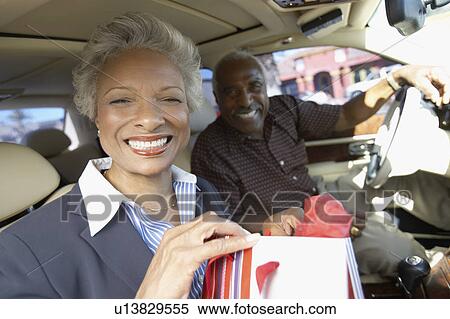 Stock Photography - Smiling Couple sitting in car, on Shopping Trip. Fotosearch