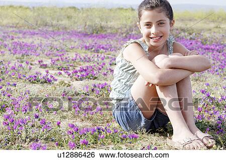 Smiling Girl sitting, arms around folded legs in Field of Flowers View Large Photo Image Stock Photograph - Smiling Girl sitting, arms around folded legs in Field of Flowers. Fotosearch