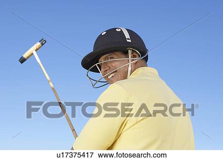 Smiling Polo Player wearing helmet with face mask, holding polo stick, back view View Large Photo Image Stock Photo - Smiling Polo Player wearing helmet with face mask, holding polo stick, back view. Fotosearch
