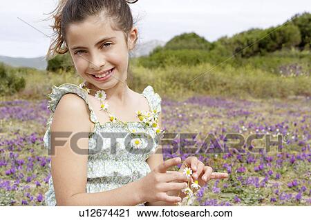 Smiling Pre-teen wearing and holding necklace of flowers in field of flowers View Large Photo Image Stock Image - Smiling Pre-teen wearing and holding necklace of flowers in field of flowers. Fotosearch