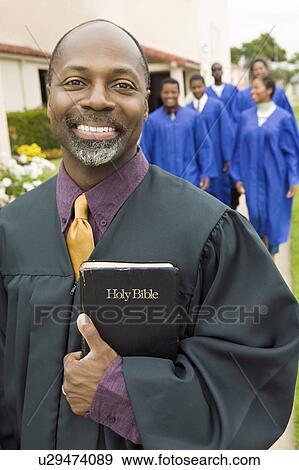 Stock Photo - Smiling Preacher on garden path, portrait. Fotosearch