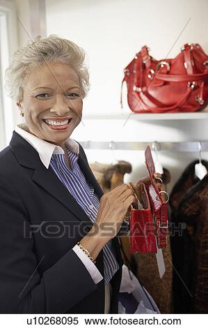 Stock Photography - Smiling senior Woman checking out purse while Shopping. Fotosearch
