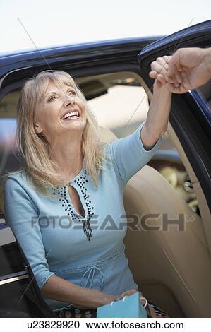 Smiling Woman getting out of car, holding Shopping Bags View Large Photo Image Stock Image - Smiling Woman getting out of car, holding Shopping Bags. Fotosearch