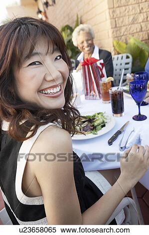 Smiling Woman sitting outdoors Having Lunch with friends View Large Photo Image Stock Photography - Smiling Woman sitting outdoors Having Lunch with friends. Fotosearch