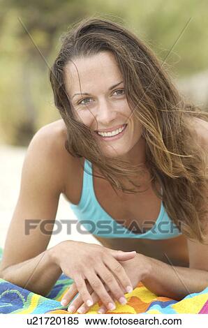 Smiling Young Woman lying down on Beach, portrait, close-up View Large Photo Image Stock Photography - Smiling Young Woman lying down on Beach, portrait, close-up. Fotosearch