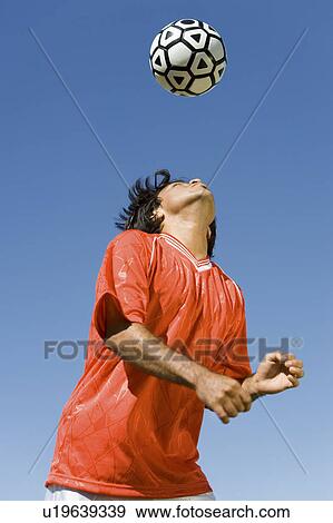 Stock Photo - Soccer player heading ball, portrait. Fotosearch