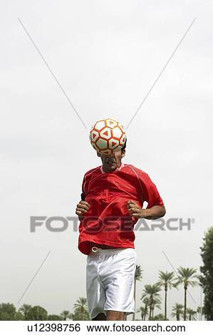Stock Photograph - Soccer player heading ball, portrait. Fotosearch