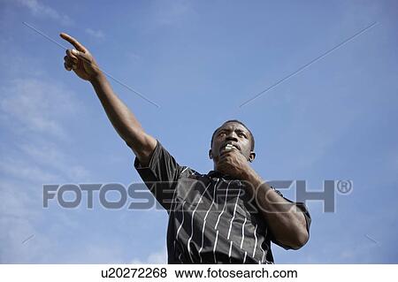 Soccer referee blowing whistle and pointing, portrait, low angle view View Large Photo Image Stock Photo - Soccer referee blowing whistle and pointing, portrait, low angle view. Fotosearch