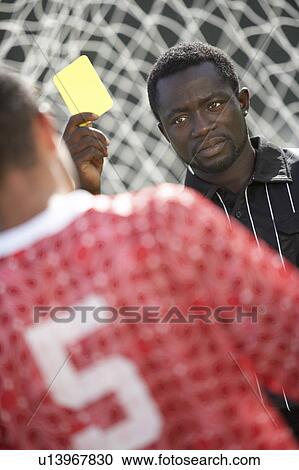 Stock Image - Soccer referee holding out yellow card, portrait. Fotosearch