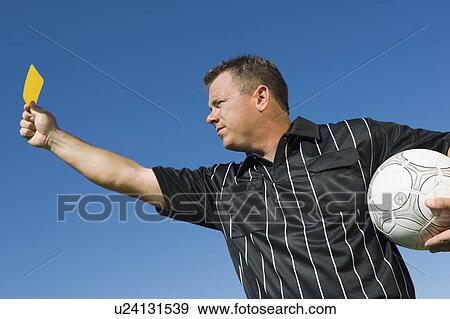 Stock Photo - Soccer referee holding yellow card, portrait. Fotosearch