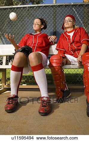 Picture - Softball players sitting on bench, low angle view. Fotosearch
