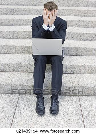 Picture - Stressed businessman using laptop on steps. Fotosearch