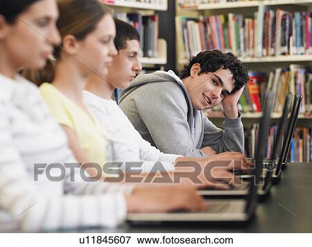 Students sitting in row using laptops in library View Large Photo Image Stock Photo - Students sitting in row using laptops in library. Fotosearch