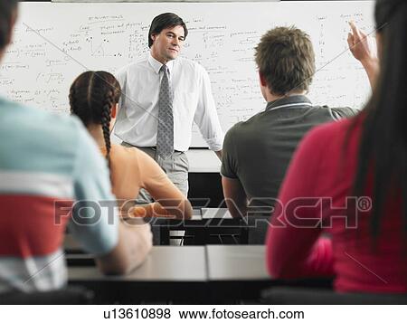 Stock Photo - Students talking to teacher in classroom. Fotosearch