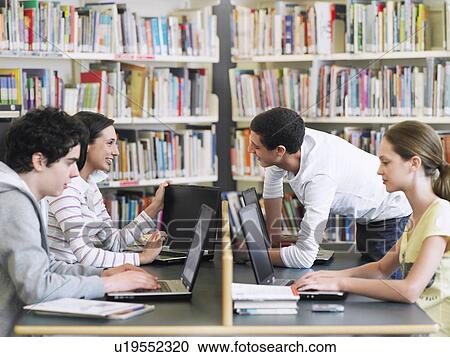 Stock Image - Students using laptops in library. Fotosearch