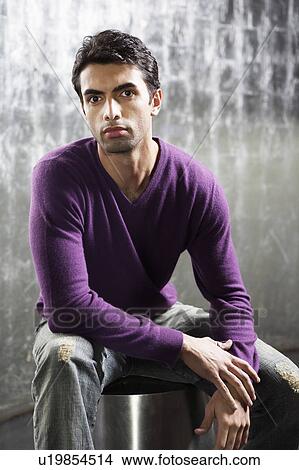 Picture - Stylish Man sitting on metal stool in metal room, portrait. Fotosearch