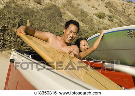 Stock Photograph - Surfer couple taking surfboards from back of truck. Fotosearch
