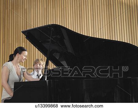 Stock Photo - Teacher with student sitting at piano in music class. Fotosearch