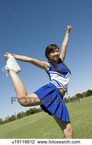 Stock Image - Teenage Cheerleader stretching on lawn. Fotosearch
