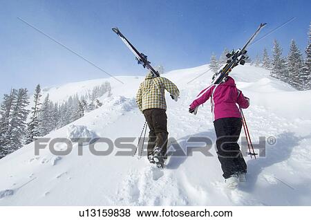 Teenage couple (16-17) holding skis, hiking up slope, back view. View Large Photo Image Stock Photo - Teenage couple (16-17) holding skis, hiking up slope, back view.. Fotosearch