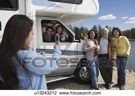 Teenage daughter photographing family with cell phone outside RV at lake View Large Photo Image Stock Image - Teenage daughter photographing family with cell phone outside RV at lake. Fotosearch