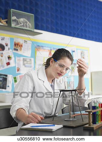 Stock Image - Teenage girl caring out experiments in chemistry class. Fotosearch