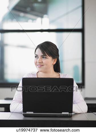 Stock Photo - Teenage girl using laptop in classroom. Fotosearch