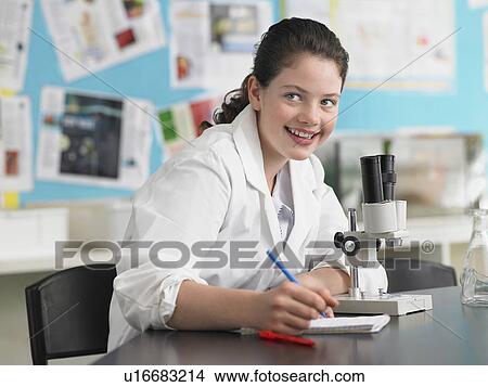 Teenage girl using microscope and taking notes in classroom, portrait View Large Photo Image Picture - Teenage girl using microscope and taking notes in classroom, portrait. Fotosearch