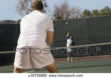Stock Photo - Tennis Player on court, Waiting For Serve, back view. Fotosearch