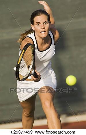 Stock Photo - Tennis Player Reaching to hit tennis ball on tennis court. Fotosearch